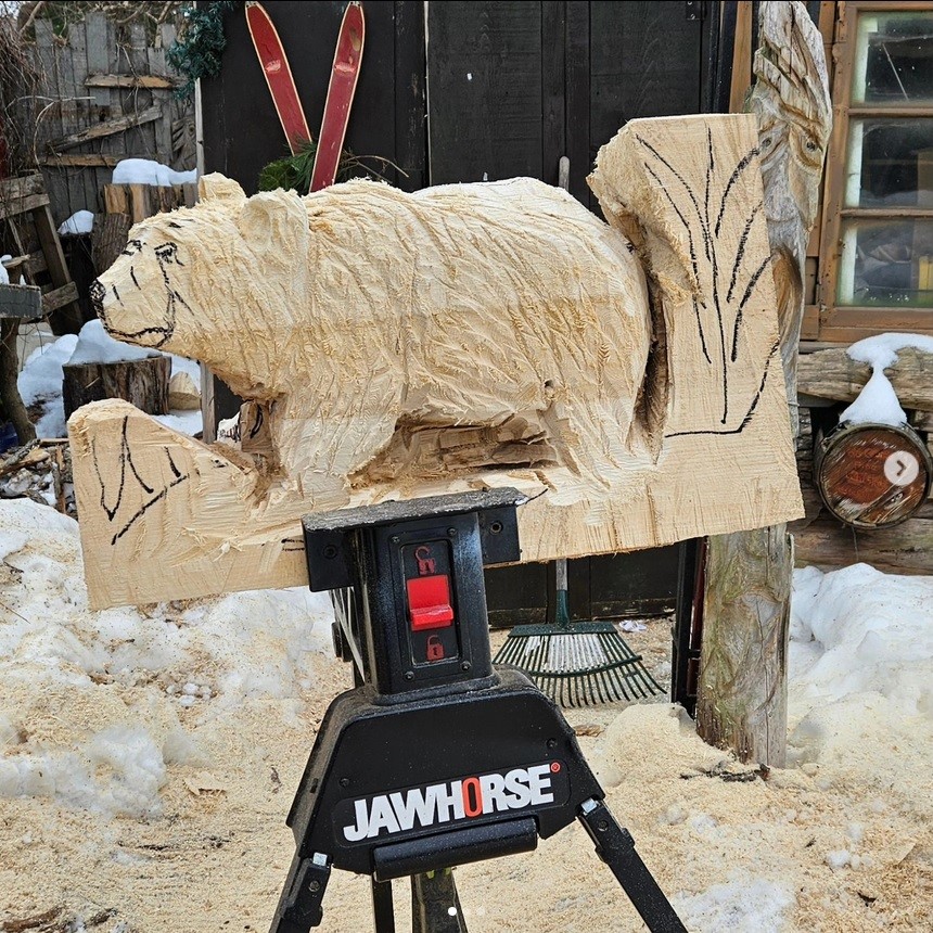 in progress wood carving of bear on a toolbench
