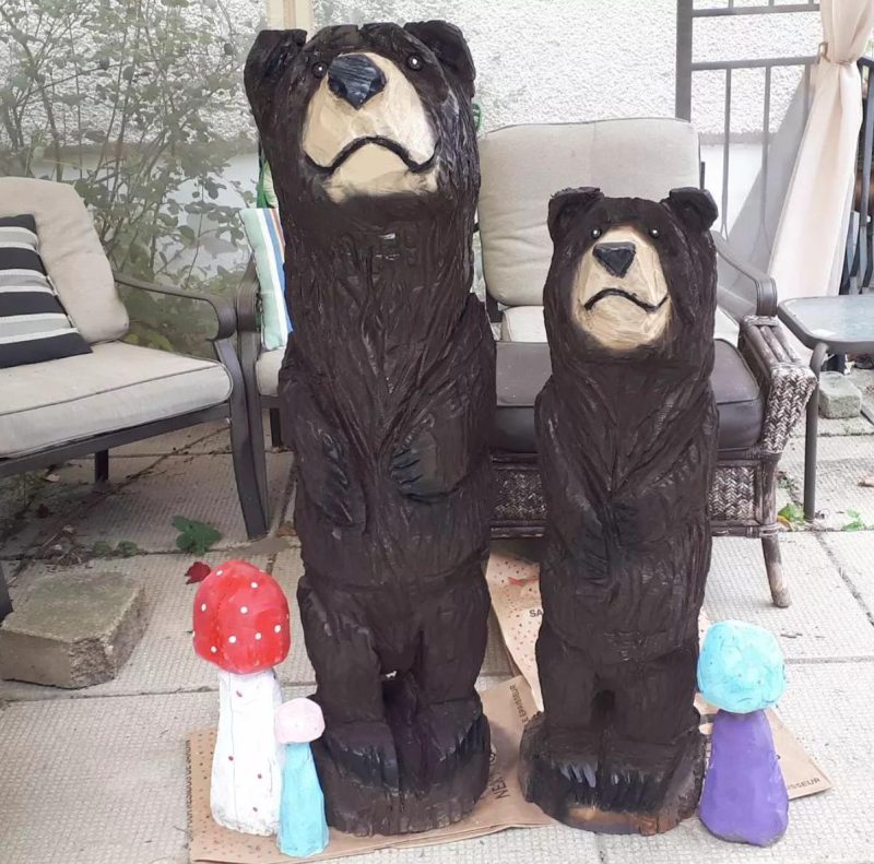 large carved black bear beside medium carved black bear with colour carved mushrooms at their feet